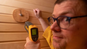 Saunologi Lassi A.Liikanen mittaa saunan lämpötilaa.