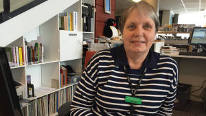 Gunilla Ritkaew läser förutom deckare gärna böcker från andra världsdelar som Afrika och Asien. Bibliotekarie sitter vid biblioteksdisk.