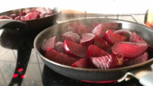 Koka rödbetorna nästan mjuka och stek dem sedan helt mjuka i salt och smör. Rödbetor som steks i en panna på spisen.