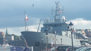 Den polska marinen är på diplomatiskt besök i Stockholm. Samarbetet med Nato-länder ökar. Ett av den polska flottans fartyg ligger vid Skeppsbron, bilar i förgrunden, stadsvy (Södermalm) i bakgrunden.