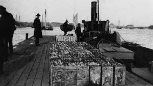 Konfiskerad sprit i Helsingfors under förbudstiden. En svartvit bild från en brygga, där flera konfiskerade spritkanistrar står på rad.