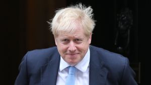 Boris Johnson är nöjd Boris Johnson iklädd mörkblå kostym, vit skjorta och ljusblå slips.