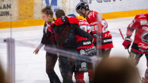 Ässäts Otto Kivenmäki leds bort från isen efter en huvudtackling. Otto Kivenmäki leds bort från isen.