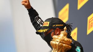 Hamilton har vunnit tre av säsongen fyra lopp. Lewis Hamilton håller upp en knytnäve och har pokalen i andra handen.