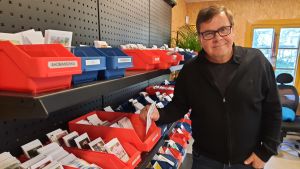 Nu planteras fröna för mångåriga blommor, säger Carl-Axel Schauman. En man håller en fröpåse intill en ställning full med fröpåsar.