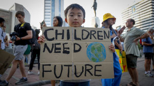 En ung pojke håller i en skylt med texten "Children need future" (barn behöver en framtid) under en klimatstrejk i Bangkok, Thailand i november 2019.
