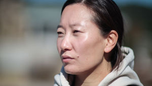 Helle Thaarup, adopterad från Sydkorea till Danmark, säger att adoption från Korea är människohandel. Närbild på kvinna med munktröja och svart hår.
