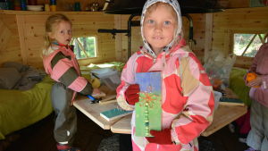 Stella Jürisson och Janna Ahonen gillar att pyssla inne i kåtan. När det regnar eller är riktigt kallt tänder man en eld i kåtan. Två barn pysslar inne i en kåta.