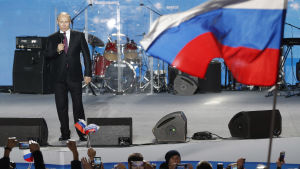 Vladimir Putin ordnade sitt sista valtillfälle inför valet på Krim, som annekterades av Ryssland 2014. presidentvalet på söndag ordnas på årsdagen av annekteringen. Vladimir Putin står på en scen intill en rysk flagga.