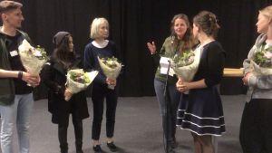 Ruth Storm Madsen Tanskan radiosta antaa palautetta finalisteille. Kuvassa vasemmalta oikealle: Tomasz Olender, Marta Martirosyan, Mathilda von Essen, Ruth Storm Madsen, Nina Eriksén ja Karen Mørk. ihmisiä tummassa studiossa kukkaasetelmat käsissä