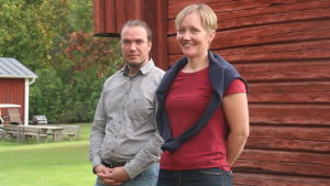 Annika Holmén och Tommy Friman träffades under en temadag vilket utmynnade i ett samarbetsprojekt. Annika Holmén och Tommy Friman står framför en rödmålad ladugårdsvägg i ett soligt sensommarväder.