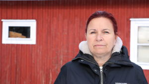 Maria-Filippa Sundlin. En kvinna med rödbrunt hår står framför en röd träbyggnad.
