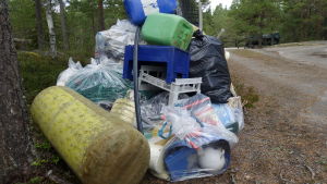 All denna plast går till förbränning. En stor plasthög i skogen. I högen finns påsar, plastbackar nät, dunkar och mycket anant skräp.