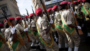 Eritrea har sen 1998 haft obligatorisk tjänstgöring på obestämd tid för alla myndiga. För många innebär det slavarbete, snarare än tjänstgöring för statens bästa. Soldater med röda baretter marscherar på en gata. I handen har de gevär som pekar rakt uppåt. Stämningen verkar uppspelt men ändå glad.
