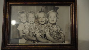 Paula, Peter, Stefan och Mikael Lumme fyra ljushåriga glada barn sitter i kö med armarna runt varandra på svartvitt fotografi i ram