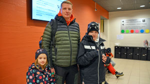 Patrik Johanssons familj besöker simhallen varannan vecka. En man och två barn i ytterkläder står inne i aulan till Borgå simhall. De ser in i kameran.
