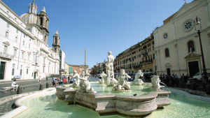 Suihkulähde, jossa useita vettäsylkeviä patsaita, Piazza Navonalla Roomassa. Talot ympäröivät aukiota.
