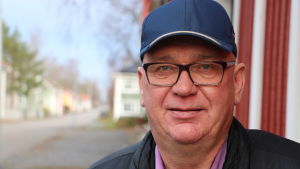 Kari Häggblom vittnar om ett spänt läge bland politikerna i Kaskö. En man med glasögon och keps står intill en husvägg.