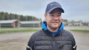 Tobias Andersson är pälsdjursuppfödare i Oravais. En man med keps står framför en rad med pälsdjurshus