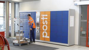 Så här kan en paketautomat se ut. Postanställd plockar in paket i paketautomater.