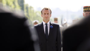 Frankrikes president Emmanuel Macron syns mellan två kostymbeklädda axlar under högtidligheter för att uppmärksamma att det gått 73 år sedan segern över Nazityskland.