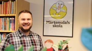 Rektor Per Wiander poserar framför en bild på skolans maskot Mårten Gås. Rektor Per Wiander vid Mårtensdals skola i Vanda.