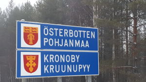 Kronoby hör till Österbotten, men är samtidigt en av medlemmarna i vårdsamkommunen Soite i grannlandskapet Mellersta Österbotten. Skylt med texten Österbotten och Kronoby på.
