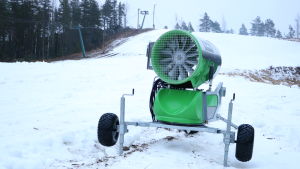 I dagens läge är snökanoner ett måste för att få backarna i skick. En grön snökanon står mitt i en skidbacke.