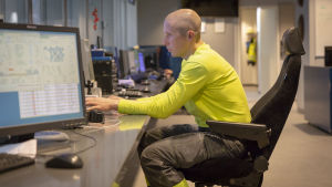 En fjärdedel av en pappersarbetares lön består av olika tillägg. Arkivbild. Ett kontrollrum. På en stol sitter en man med rakad skalle vid en dator.