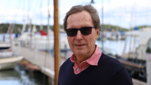 Henrik Brenner anser att det är viktigt att alla har grundläggande segelkunskaper. Äldre man står med solglasögon på brygga i Nagu.