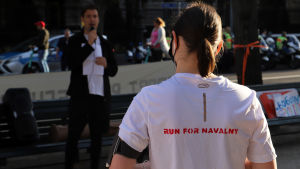 Demonstration framför den ryska ambassaden i Berlin. En kvinna som bär en tröja med texten "Run for Navalny" på ryggen