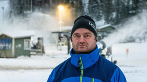 Problemen med tanke på coronaviruset uppstår främst inomhus, enligt vd Niklas Blomander vid skidcentret i Kokon. Niklas Blomander står framför en snökanon och en slalombacke