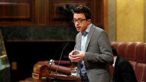 Iñigo Errejon är ordförande och grundare av Más País. En man i grå kostym står i en talarstol.
