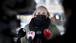 Inrikesminister Maria Ohisalo (Gröna) sa att situationen är svår. Inrikesminister Maria Ohisalo i svart munskydd och ytterkläder. Hon talar till reportrar vid Ständerhusets trappa i Helsingfors. Framför henne syns Yles, Iltalehtis, MTV:s och Ilta-Sanomats mikrofoner.