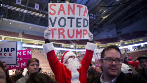 En man utklädd till jultomten håller upp en skylt"Jultomten röstade på Trump"