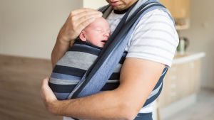 Pappor ska få vara hemma och mysa med sina barn längre. En pappa vars ansikte inte syns håller ett barn mot sitt bröst.