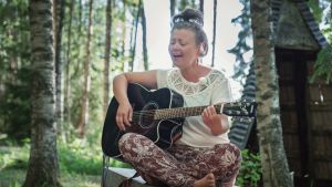 Niinimäki är sångare och låtskrivare som uppträder med artistnamnet Heiduška, både som soloartist och med sitt band från Joensuu. Hon förnimmer ett samband mellan sin musik och skulpturernas ande. Nainen istuu penkillä risti-istunnassa, soittaa kitaraa ja laulaa, taustalla keväistä metsää