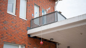 En fotboll hänger från ett snöre från en balkong och på balkongräckte står en rad bordsflaggor.