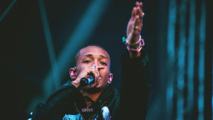 Jaden-nimellä esiintyvä Jaden Smith on myös hyväntekijä, vaatesuunnittelija ja tyyli-ikoni. Räppäri Jaden Smith räppää Blockfestin lavalla käsi ojennettuna eteenpäin. Taustalla sinertävät visuaalit.
