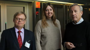 Vänsterpolitikern Mia Haglund (i mitten) backar från kraven på ett förmögenhetstak på 10 miljoner euro. Men hon tycker att frågan är viktig, och får medhåll av Juhana Vartiainen (till vänster) och Sixten Korkman (till höger). Vartiainen, Haglund och Korkman poserar framför en hissdörr.