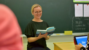 Just nu är det Pärlfiskaren av Karin Erlandsson som är högläsningsbok i femman där Catharina Engblom är lärare. Lärare sitter med bok i klassrum.