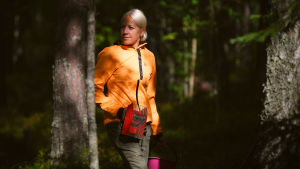 Mäkäräinen uppskattar lugnet i den nya vardagen. kaisa i skogen med bärplockare och hink i handen