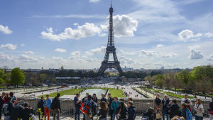 Många vill se Eiffeltornet i Paris. Eiffeltornet i Paris med turister i förgrunden.