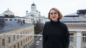 Isabella Holm på en balkong utanför Reaktors kontor invid Helsingfors universitet och Helsingfors domkyrka. Isabella Holm