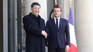 Frankrikes president Emmanuel Macron och Kinas president Xi Jinping skakar hand med varandra.
