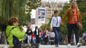 Centrala Pristina var tapetserat med valaffischer inför söndagens val. Människor går framför en valaffisch i Pristina.