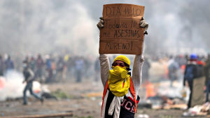 Kraftiga demonstrationer i Ecuador i oktober 2019. Mielenosoittaja pitelee päänsä yläpuolella kylttiä, jossa lukee: "Päivä numero 10. Sinun ei pitäisi vielä tappaa minua, Moreno!"