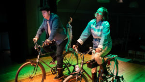 Presidentparet eller deras alteregon tar sig en cykeltur i lokala landskap. (Matti Raita och Sanna Hietala). Presidentparet eller deras alteregon tar sig en cykeltur i lokala landskap. (Matti Raita och Sanna Hietala).