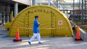 Ett tält för coronapatienter vid ingången till Karolinska sjukhuset i Stockholm 19.3.2020 En sjukskötare går utanför ett gult tält.