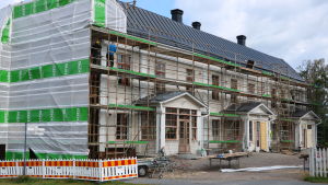 Södra gaveln (till vänster i bilden) är hårt utsatt för väder och vind. En byggnad som renoveras. Byggställningar är placerade runt huset.